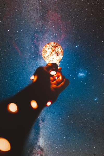 Hand holding lightbulb in space