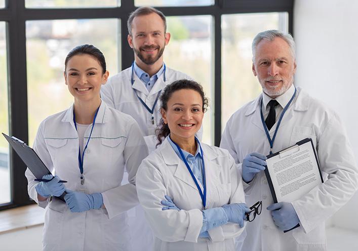 A group of four smiling scientists or healthcare professionals in white lab coats posing for a photo.